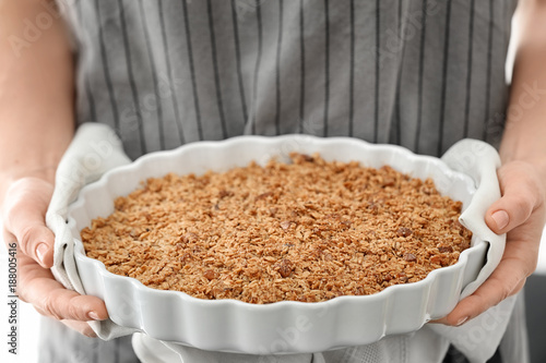 Woman holding baking dish with apple crisp, closeup