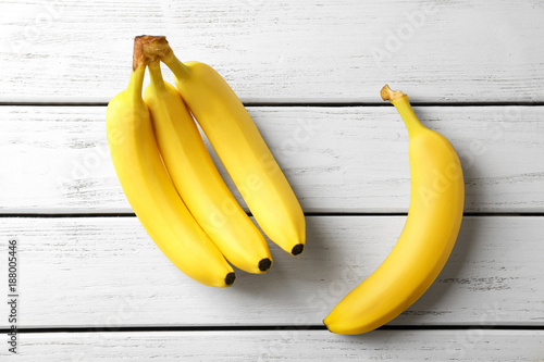 Tasty ripe bananas on white wooden background