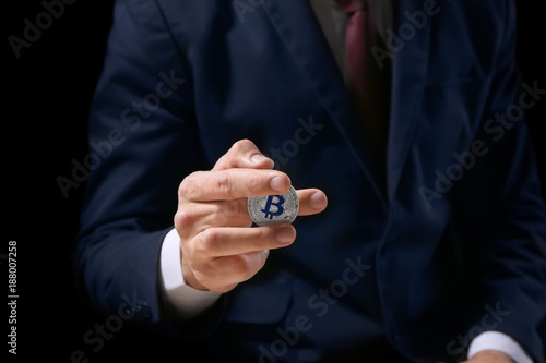 Man holding silver bitcoin between his fingers, closeup
