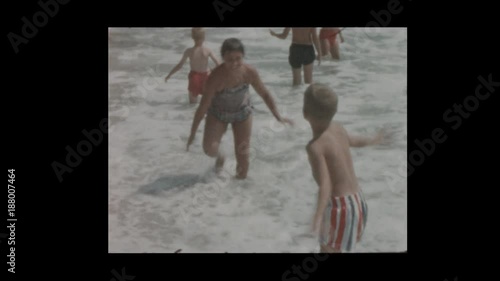 1956 50's kids frollic in surf at the beach photo