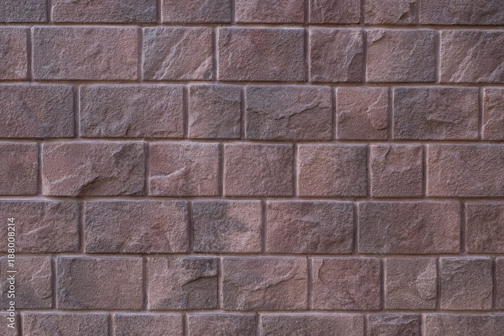 Fototapeta premium red stone wall background, Large stone-clad facade brown color.