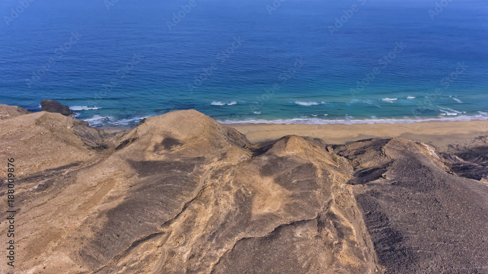 View from volcanic rocky mountain towards sandy beach and blue sea . View from volcanic rocky mountain towards sandy beach and blue sea .