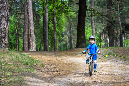 Happy cute blond kid boy having fun his first bike on sunny summer day, outdoors. Happy child making sports. Active leisure for children.Kid boy wear safety helmet. boy is smiling and cicling. © pahis