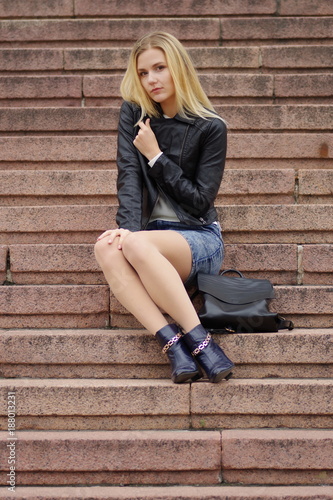 Pretty young blonde girl sits on a marble stairs