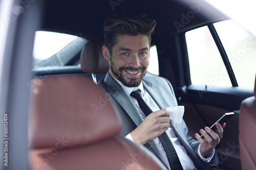 Businessman drinking coffee in car with phone in hand © ASDF