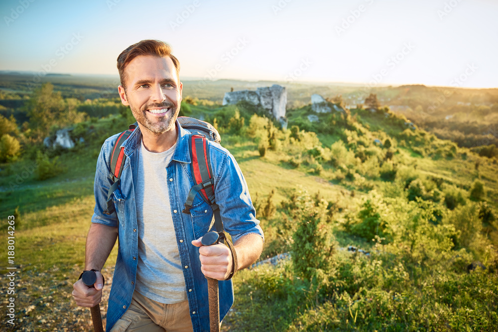 © baranq - Smiling man hiking in the mountains using poles and looking away © baranq - Smiling man hiking in the mountains using poles and looking away