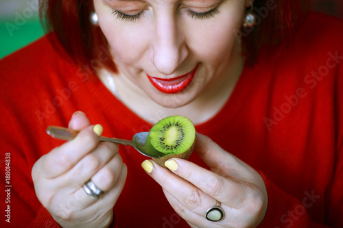 Beautiful young woman eating ripe and juicy fruit KIWI photo