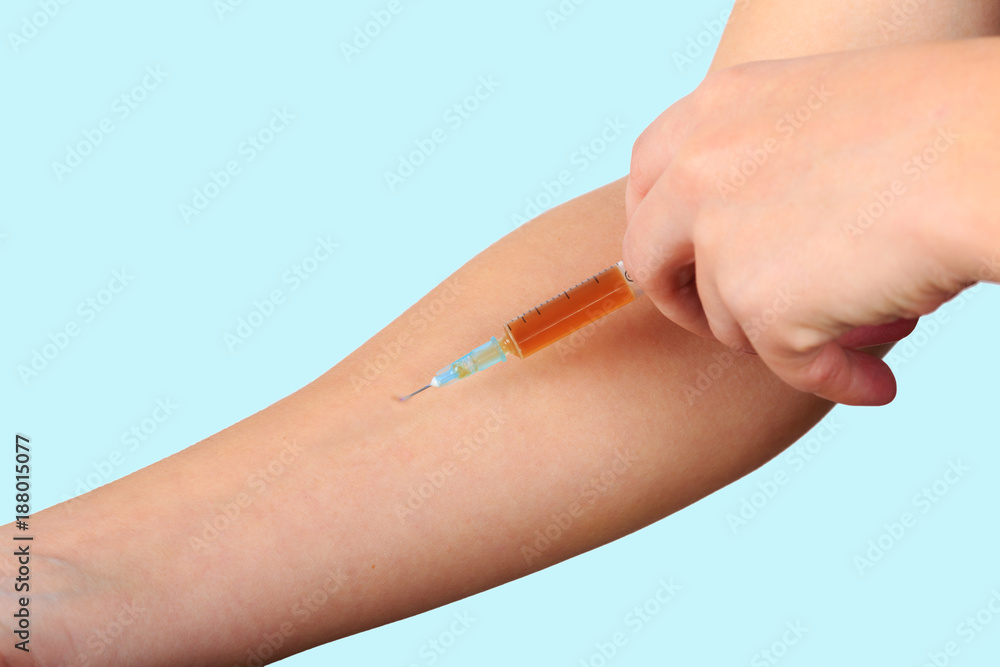 Close-up of hand, giving vaccination to patient using a syringe with brown drugs. Sterile injection in the upper arm. Close-up of hand, giving vaccination to patient using a syringe with brown drugs. Sterile injection in the upper arm.