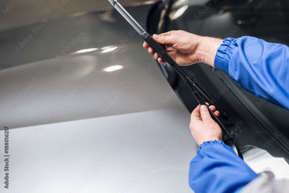 Fotografie Technician is changing windscreen wipers on a car station.
