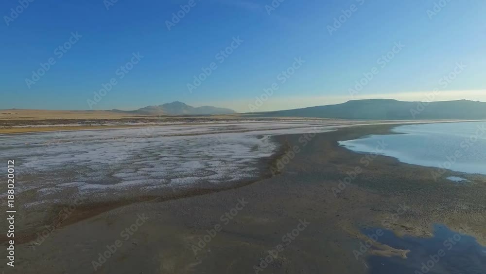 Aerial view of a beach with snow on the sand and the mountains in the distance Aerial view of a beach with snow on the sand and the mountains in the distance