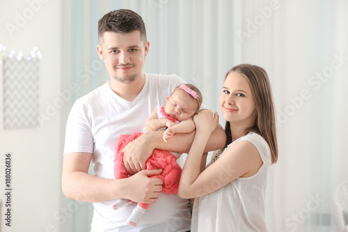 Happy young family holding cute sleeping newborn baby at home