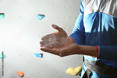 Young man applying talc powder on hands in climbing gym