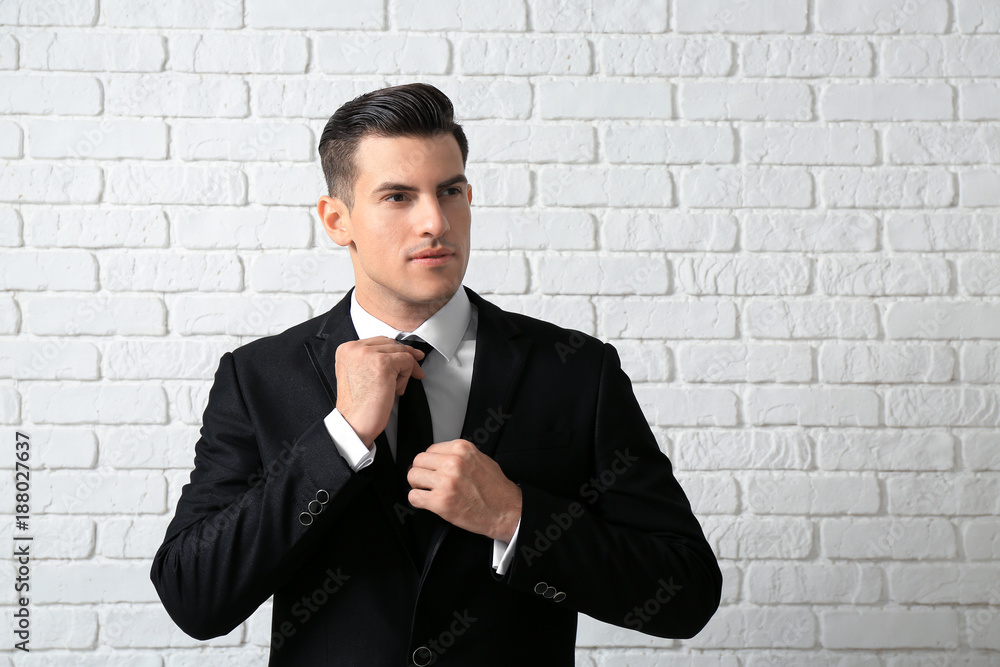 Handsome man in elegant suit near white brick wall Handsome man in elegant suit near white brick wall