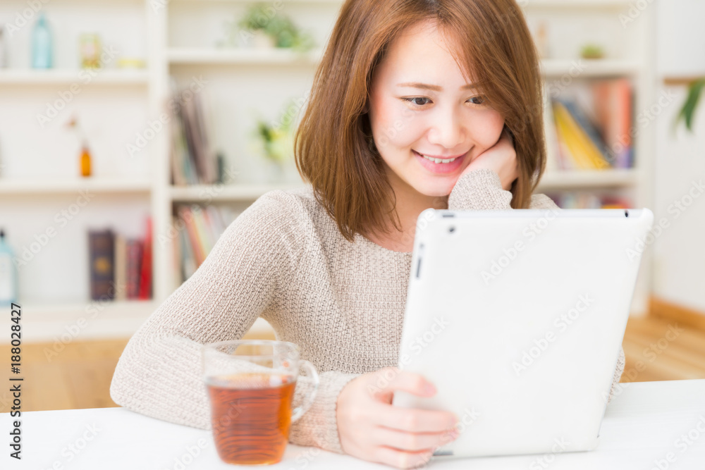 部屋でタブレットを見る女性 部屋でタブレットを見る女性