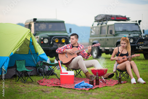 group of adventure tourist enjoy camping by playing guitar and song a song with barbecue etertaine over night campfire tents and adventure compatible off road car © ID_Anuphon