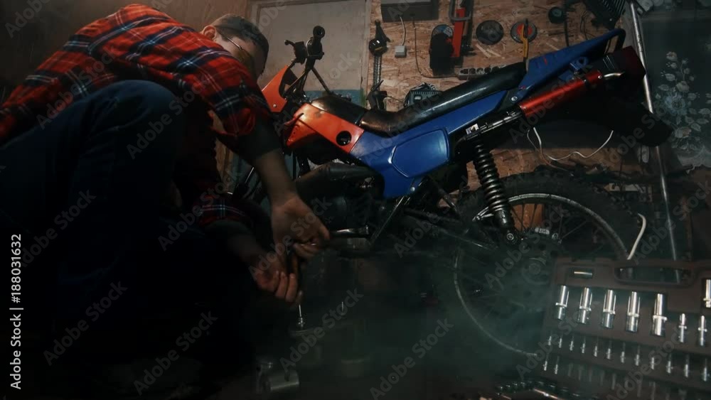 male mechanic repairing the engine of a motorcycle in the garage male mechanic repairing the engine of a motorcycle in the garage