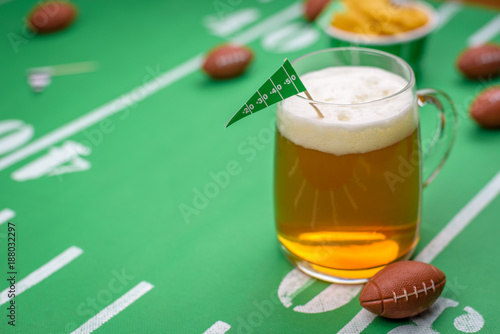 large glass mug of cold beer on table with superbowl party decorations
