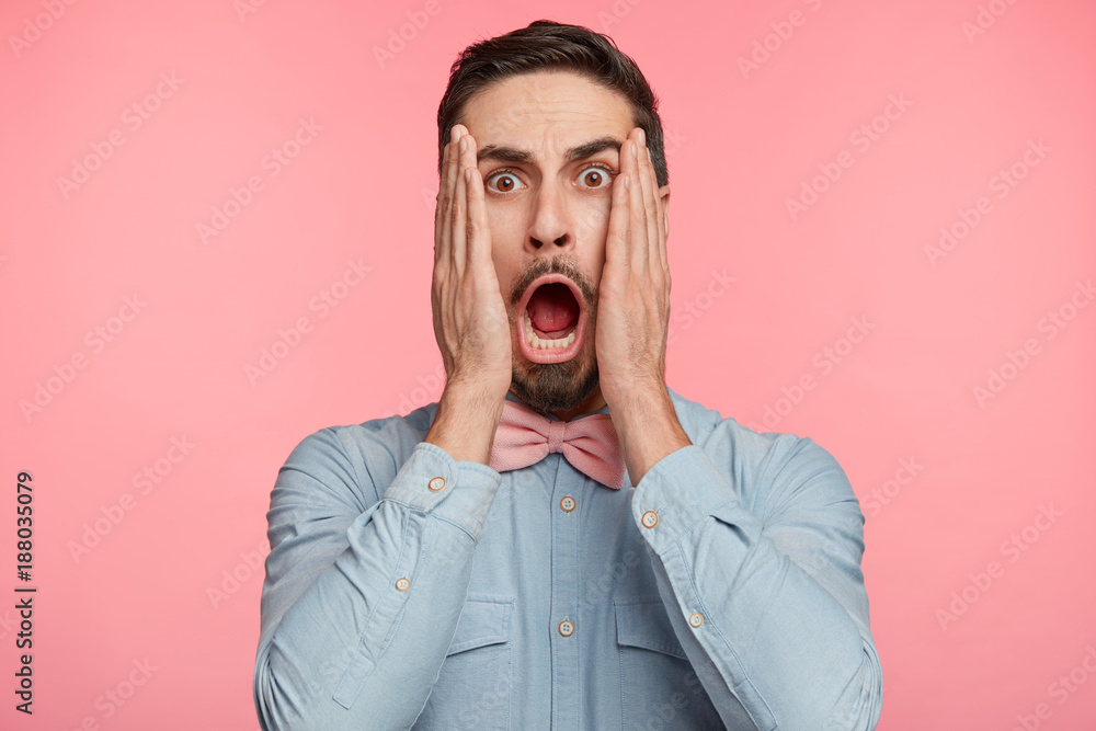 Terrified shocked scared male keeps mouth opened, looks with amazed expression at camera, isolated over pink background. Unshaven stylish man in elegant clothes expresses great wonder, poses indoor Terrified shocked scared male keeps mouth opened, looks with amazed expression at camera, isolated over pink background. Unshaven stylish man in elegant clothes expresses great wonder, poses indoor