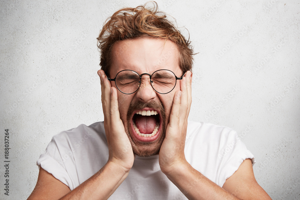 Close up portrait of crazy stressful male screams in panic and terror, being fed up with everything, closes eyes in despair, yells loudly, isolated over white background. Emotions and feelings concept Close up portrait of crazy stressful male screams in panic and terror, being fed up with everything, closes eyes in despair, yells loudly, isolated over white background. Emotions and feelings concept