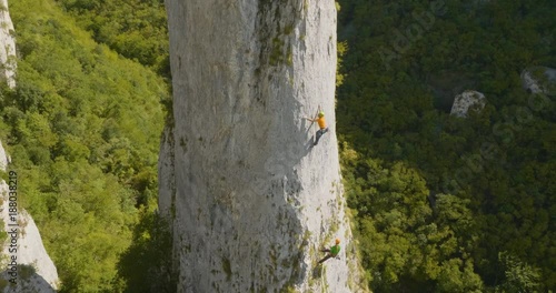 Aerial side shot of amazing climbers climbing the rock in nature on a summer day.

