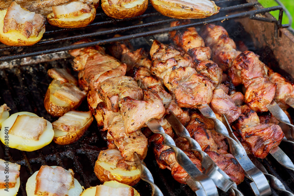 Raw kebab grilling on metal skewer. Meat roasting at barbecue with vegetables. BBQ fresh beef chop slices.