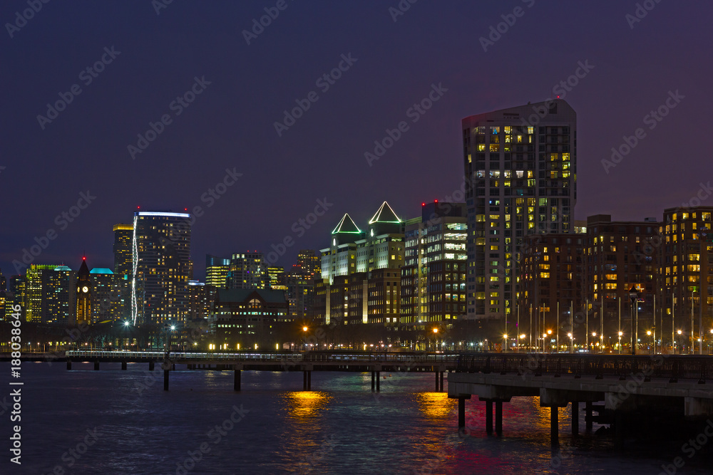 Hoboken waterfront on Hudson River at night in winter, New Jersey, USA. City urban panorama with reflection from colorful buildings and street lights.