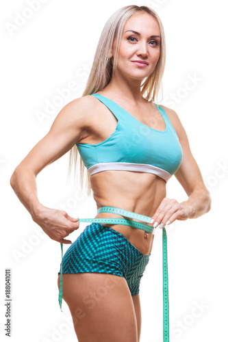 Athletic slim woman measuring her waist by measure tape after a diet over black background