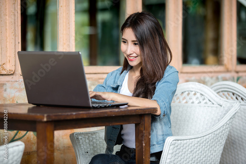 Beautiful Asian self employed or freelance business woman working with her laptop PC at the restaurant terrace
