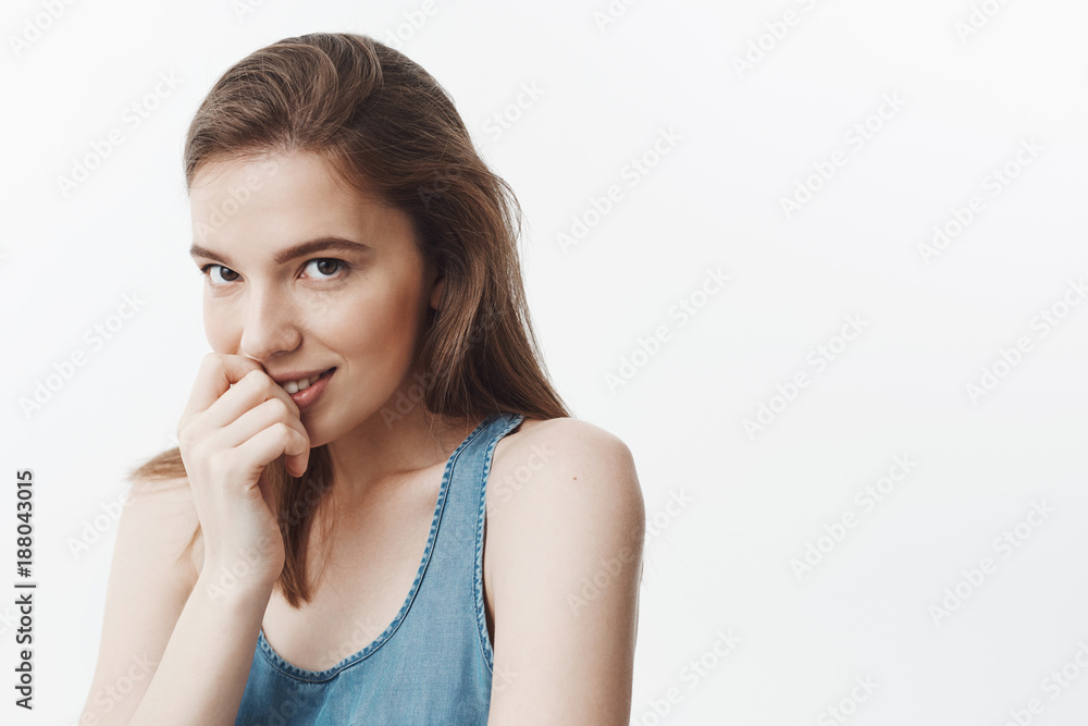 Good-looking sexy charming young european woman with dark long hair in blue shirt holding hand near lips, looking in camera with relaxed and flirty face expression, staring on guy siting in front of Good-looking sexy charming young european woman with dark long hair in blue shirt holding hand near lips, looking in camera with relaxed and flirty face expression, staring on guy siting in front of
