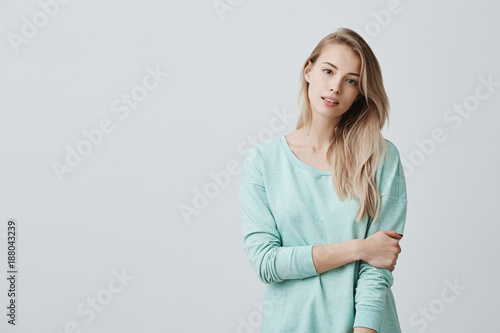 Cheerful european girl with parted lips, rejoicing her life, dressed casually standing isolated against grey wall background. People, beauty, youth and happiness concept