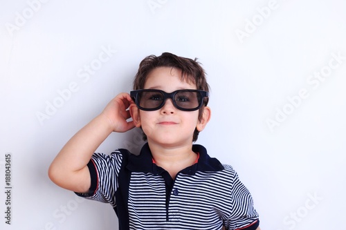Happy lovely smiling boy in sunglasses, studio shoot on white. Children, fashion and lifestyle concept