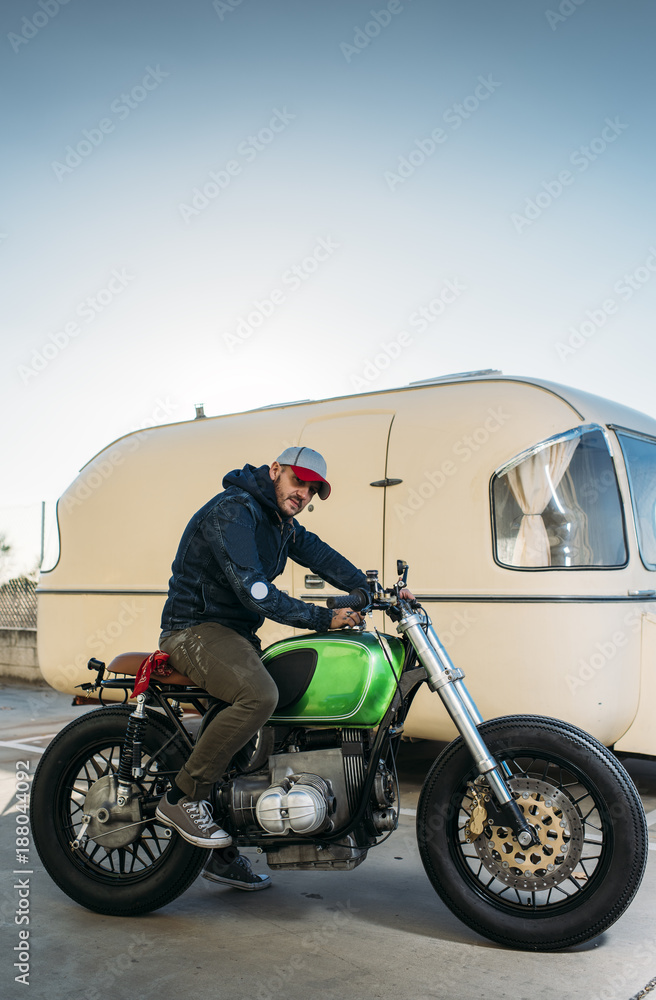 Stylish man on motorcycle near a van Stylish man on motorcycle near a van