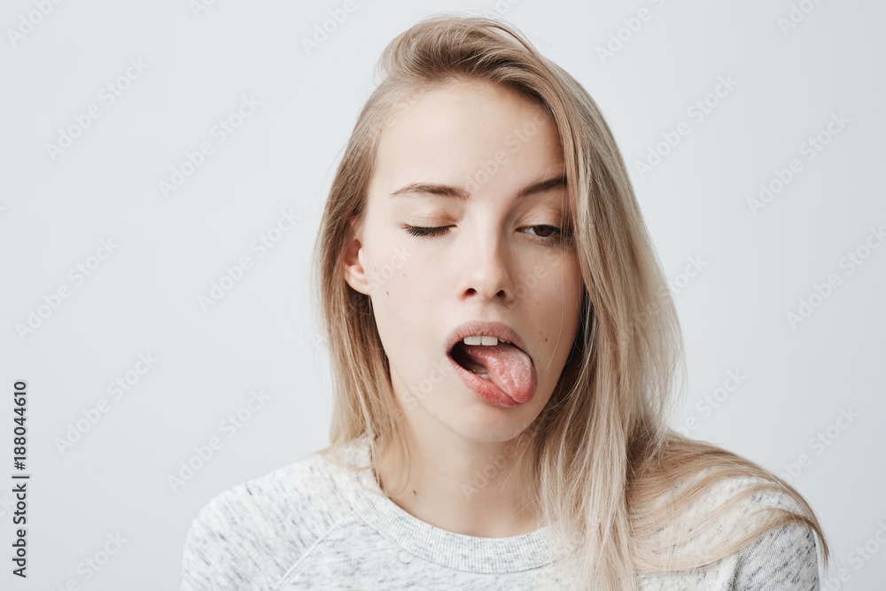 Headshot Of Naughty Girl Of European Appearance With Blonde Long Hair Sticking Out Tongue