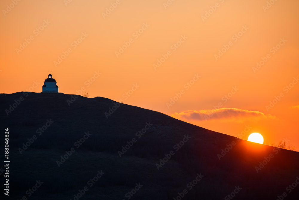 Church on mountain Hill, silhouettes on sunset