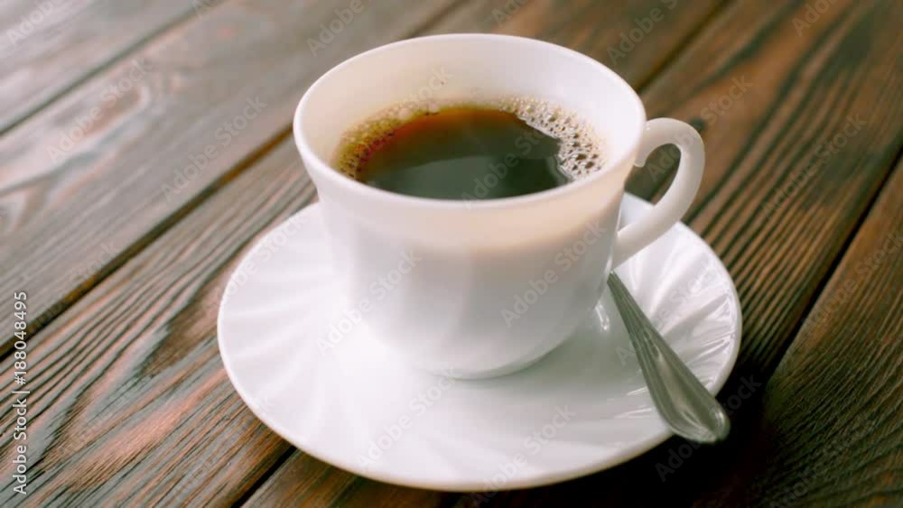 A cup of hot coffee stands on a wooden table A cup of hot coffee stands on a wooden table