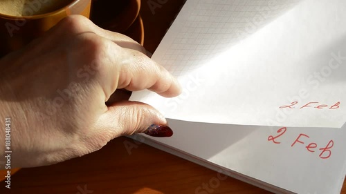 Female hand leafing through a notebook with duplicate date - February 2 photo