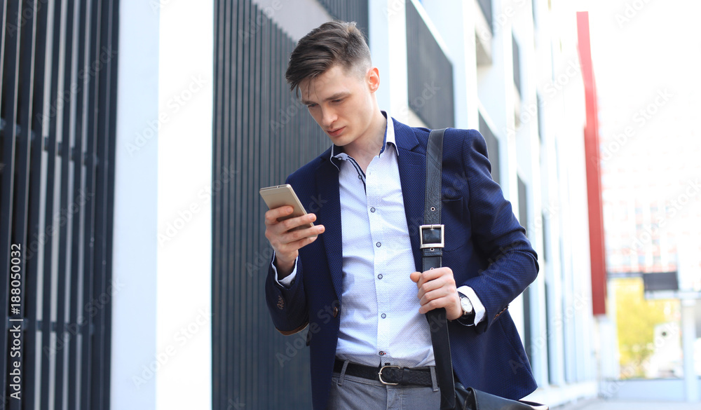 Fototapeta premium Young urban businessman professional on smartphone walking in street using mobile phone.