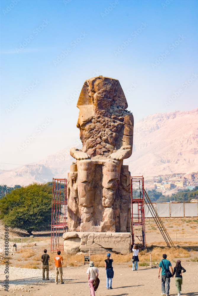 Luxor, Egypt. February 19, 2017: View of one of the memnon colossi dedicated to the pharaoh Amenhotep III and located at the osete and near the city and surrounded by scaffolding for restoration