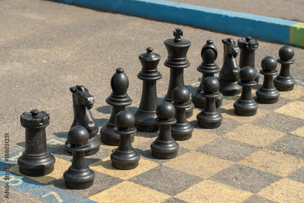 Large chess pieces on the asphalt in summer