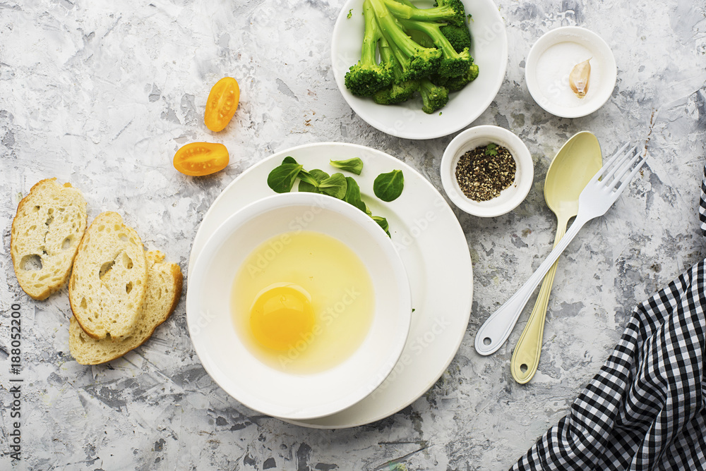 Ingredients for cooking scrambled eggs or omelets with green herbs, fresh vegetables, broccoli and turmeric as a healthy breakfast or lunch option. View from above. Against a light background. Ingredients for cooking scrambled eggs or omelets with green herbs, fresh vegetables, broccoli and turmeric as a healthy breakfast or lunch option. View from above. Against a light background.