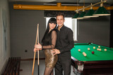 Sexy couple playing billiards. A party
