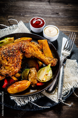 Barbecued chicken leg with baked potatoes and vegetables
