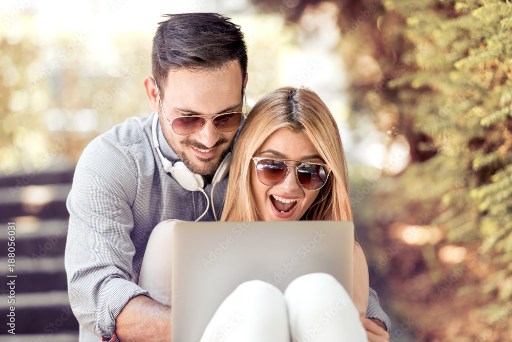 Portrait of happy couple sitting together outdoors with laptop Portrait of happy couple sitting together outdoors with laptop