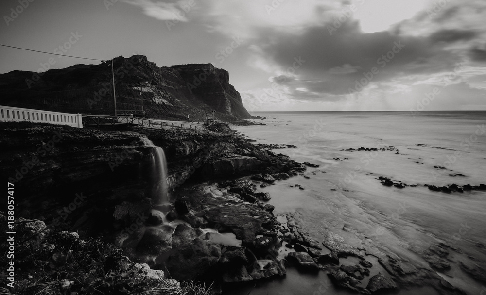 Waterfall runs to the sea in a coastline at the sunset. Long exposure. Portugal