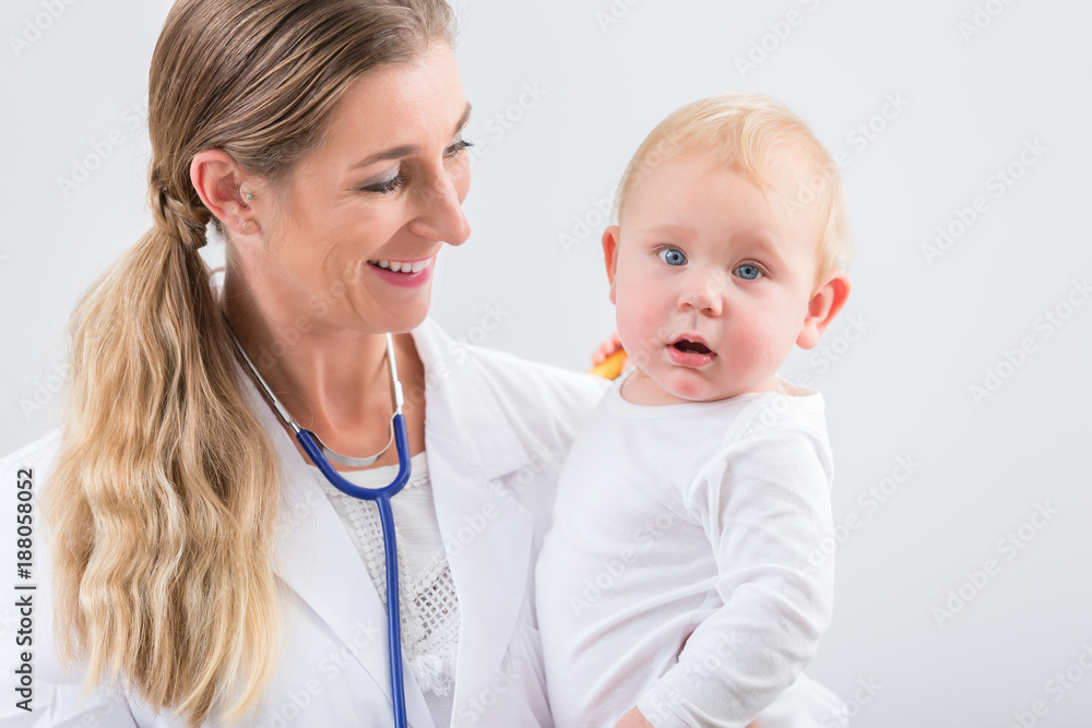 Portrait of a dedicated female physician and pediatric care specialist, smiling while holding a cute and healthy baby girl at the hospital or in a medical healthcare center Portrait of a dedicated female physician and pediatric care specialist, smiling while holding a cute and healthy baby girl at the hospital or in a medical healthcare center