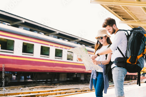 Multiethnic traveler couple, backpacker tourist, or college student using generic local map navigation together at train station platform. Asia tourism trip, outdoor backpack adventure travel concept