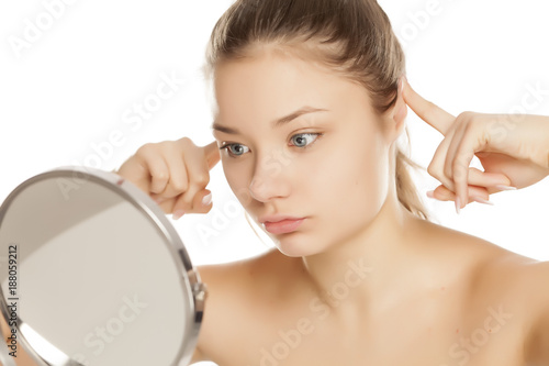 young girl checking her ears in the mirror on white background