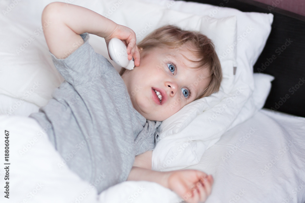 Measuring baby's temperature with contactless digital infrared thermometer in the ear. 2 years old kid measures its temperature in the ear himself Measuring baby's temperature with contactless digital infrared thermometer in the ear. 2 years old kid measures its temperature in the ear himself