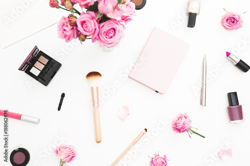 Beauty workspace with pink roses bouquet, cosmetics, diary on white background. Top view. Flat lay home feminine desk. Fashion blog