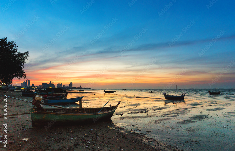 Landscape of tropical beach with old fishing boat parked on the beach in twilight sunset in Pattaya, Thailand